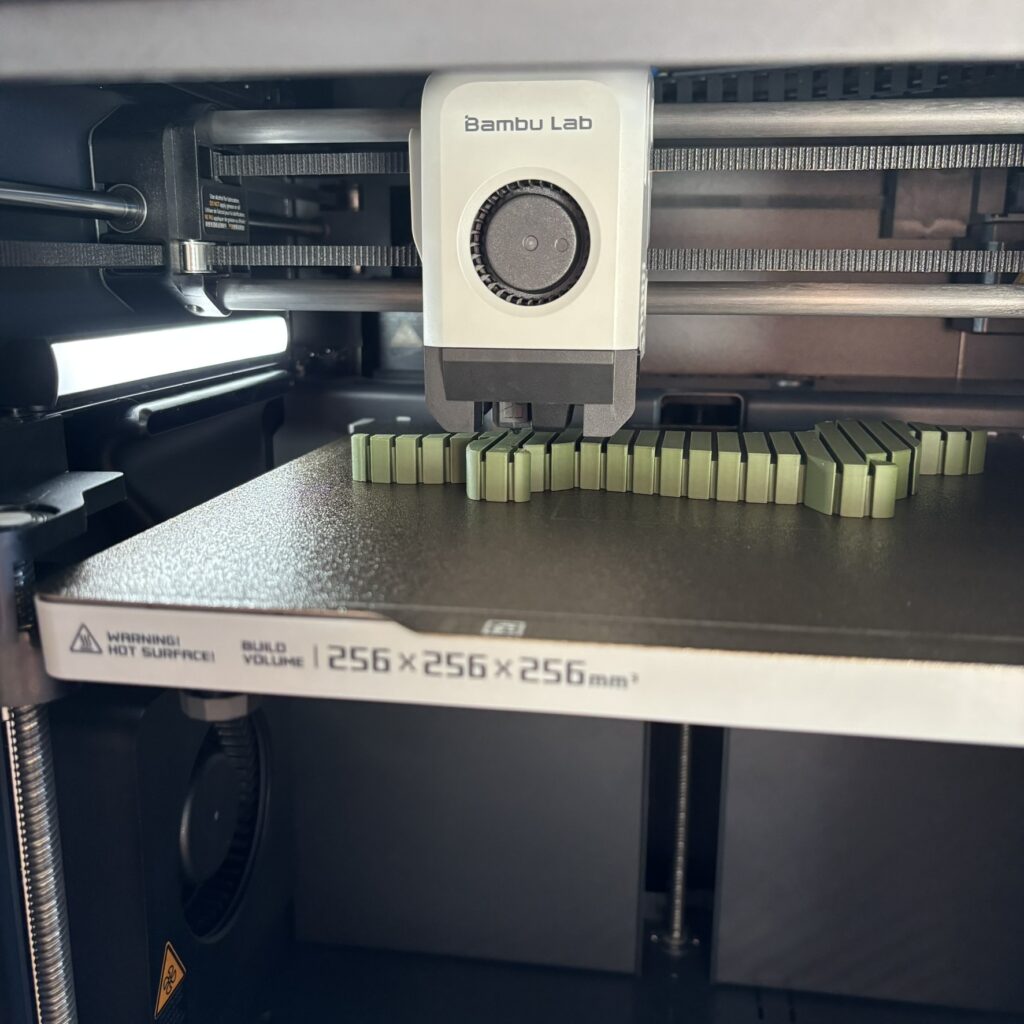 Eine Dackelfigur entsteht Schicht für Schicht in einem 3D-Drucker bei Amvelon.